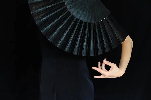 Woman behind a black fan, mention flamenco dancing
