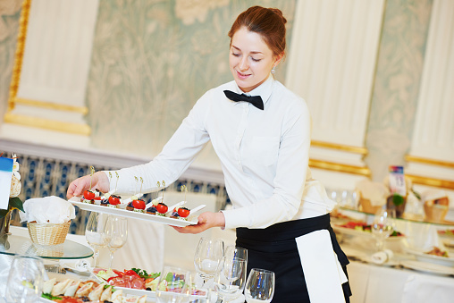 waitress occupation. Young woman with food on dishes servicing in restaurant during catering the event