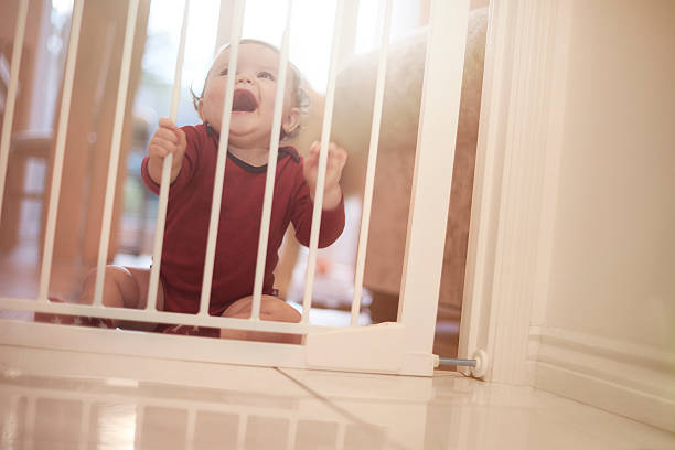istock Baby boy laughing behind baby safety gate 520012248
