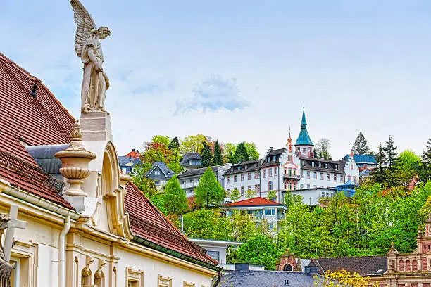 Panoramic view of Baden-Baden city and the angel sculpture. Baden-Baden is a spa town. It is situated in Baden-Wurttemberg in Germany. Its church is called Stiftskirche.