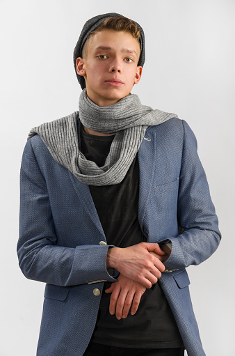Portrait of a young artist wearing scarf and cap, against gray background