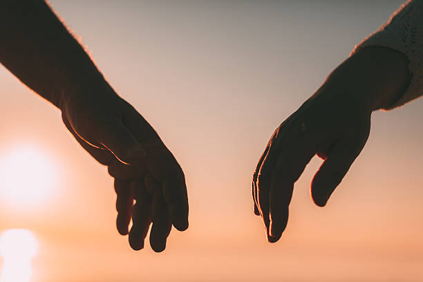 istock Couple hands reach silhouette on a sky and sea background 520015122