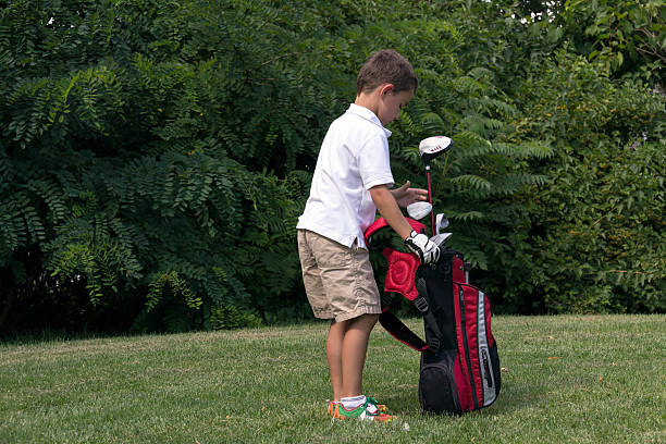 Little boy golfer with golf bag on the fairway stock photo