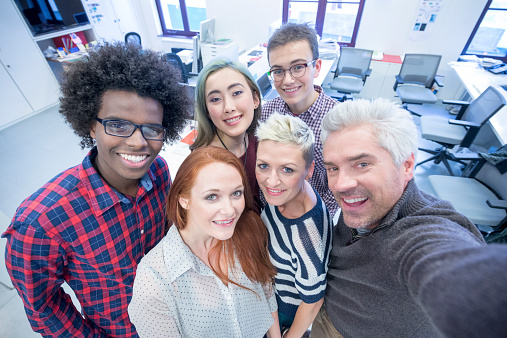Casual business people taking group selfie. Team selfie in modern office.