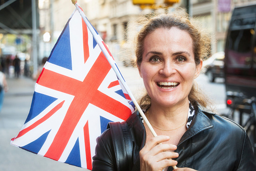 Smiling mature woman holding and waving a British flag