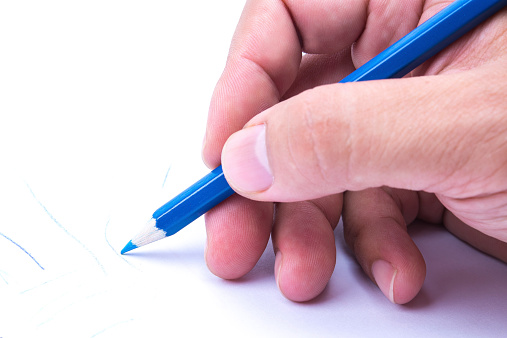 Close-up of person's hand sketching on white background.
