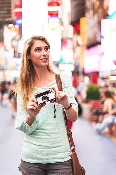 istock pretty woman smiling on times square with camera 520019591
