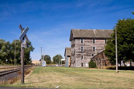Historic flour mill beside the railroad tracks and crossing sign, Oakesdale , Palouse Valley, eastern Washington State