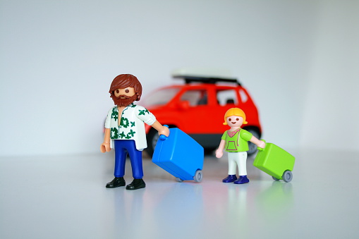 Alcobendas, Spain - July 20, 2014: a man toy and his daughter start the holidays traveling in a car. They carried its suitcases. On white background. The Playmobil toy line exists since 1975 and is produced by the german Company Brandstaetter.