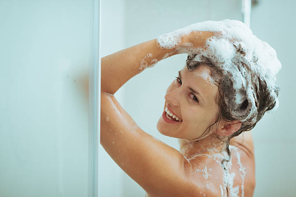istock smiling young woman washing head with shampoo 520021043