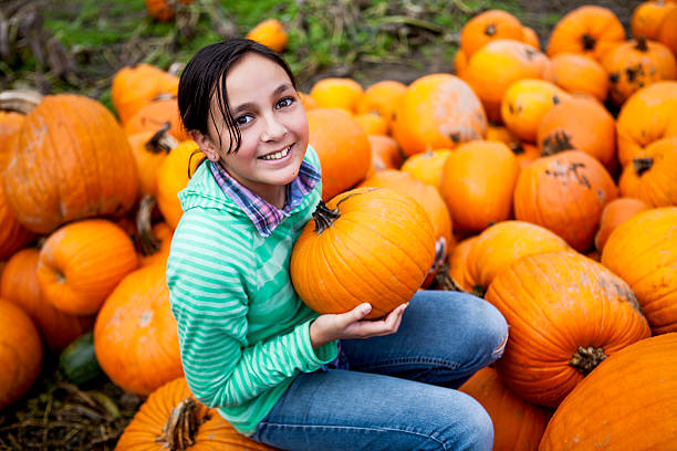 ragazza sorridente e tenendo una zucca - pumpkin child little girls pumpkin patch foto e immagini stock