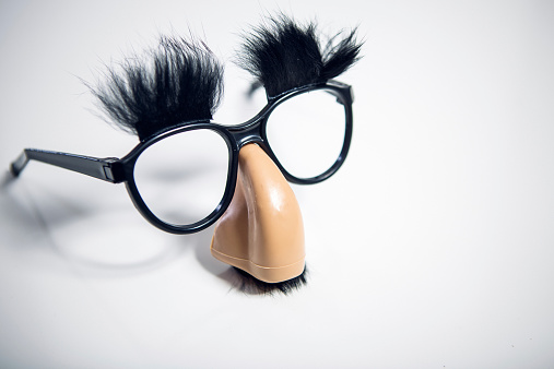 A pair of vintage looking funny costume glasses, with an oversize nose, mustache, and eyebrows attached.  The perfect disguise for hiding looking suspicious when you're trying to not raise suspicion.   Horizontal with copy space.