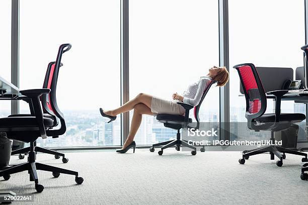 Young Businesswoman Leaning Back In Chair At Office Stock Photo - Download Image Now