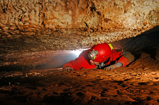 Narrow cave passage with a spelunker explorer