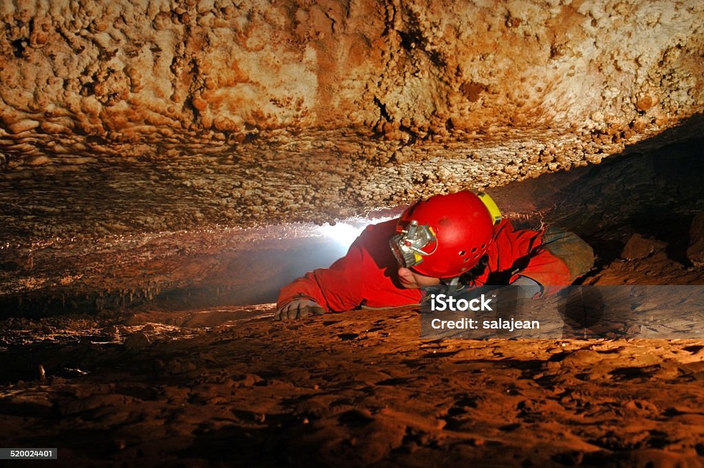 Narrow cave passage with a cave explorer Narrow cave passage with a spelunker explorer Spelunking Stock Photo