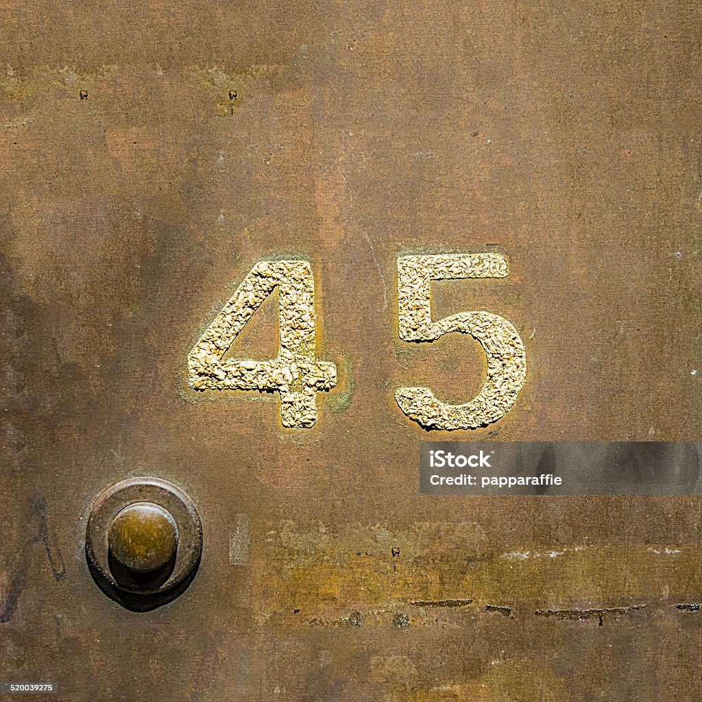 Number 45 House number forty five on a kopper plate next to  a door bell. Number Stock Photo