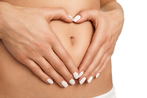 Pregnancy or diet concept, female hands forming heart shape on the stomach