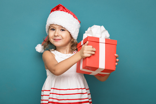 Baby Playing Santa Claus Under Christmas Tree And Holding Bauble In Hand