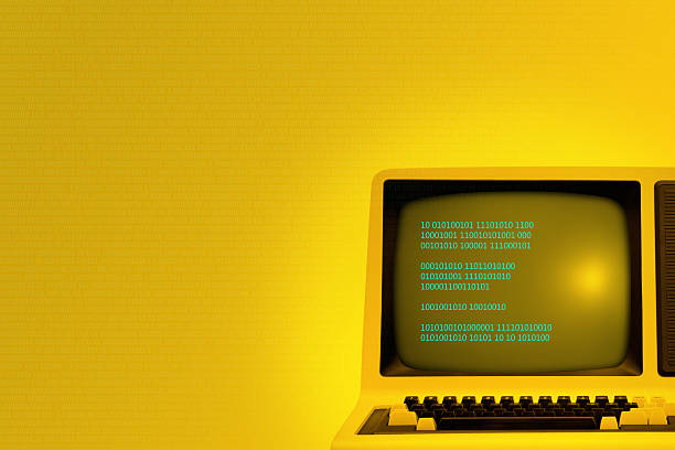 Vintage computer technology background with binary code Vintage technology yellow background with old computer showing binary code on its monitor. Code spreads across image area. Retro revival of seventies devices. Plenty of copy space on the side. Low-key background for easy costumization.  computer mainframe old retro revival stock pictures, royalty-free photos & images