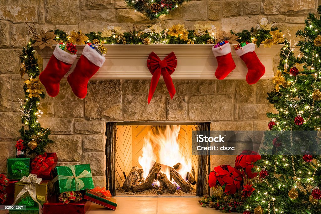 Christmas fireplace, tree, stockings, fire, hearth, lights, and decorations Christmas fireplace, tree, decorations, lights, mantel, hearth. Christmas Stock Photo