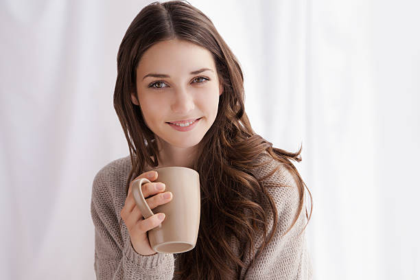 istock beautiful woman drinking coffee, sitting by window 520042809