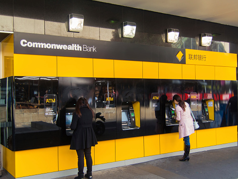 Melbourne, Australia - August 22, 2014: two women accessing cash from automatic teller machines outside the Box Hill branch of the Commonwealth Bank in suburban Melbourne. The Commonwealth Bank is one of Australia's four large national banks.