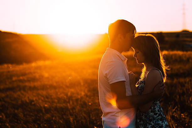 istock Romantic couple standing and kissing on background summer meadow sunset 520051656