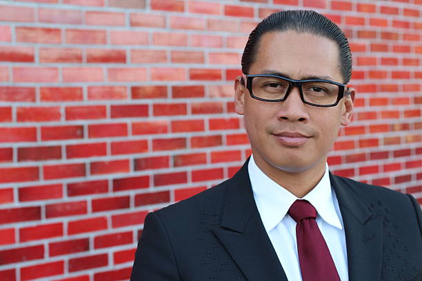 A happy Filipino professional with a confident look (isolated on a red brick wall).