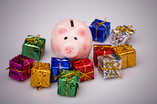 Pig money box between christmas gift on white background