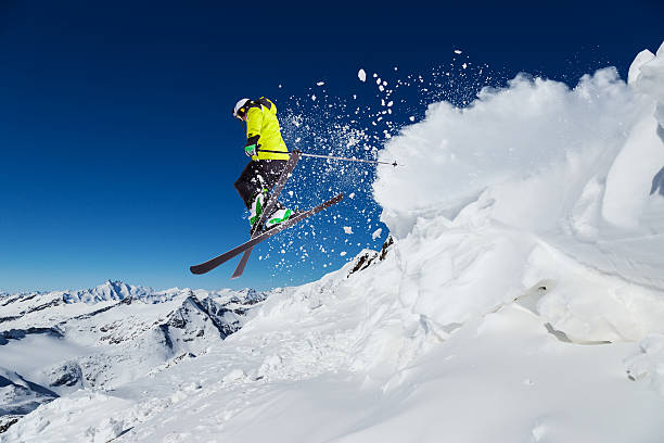 Alpine skier on piste, skiing downhill Alpine skier skiing downhill, blue sky on background powder mountain stock pictures, royalty-free photos & images