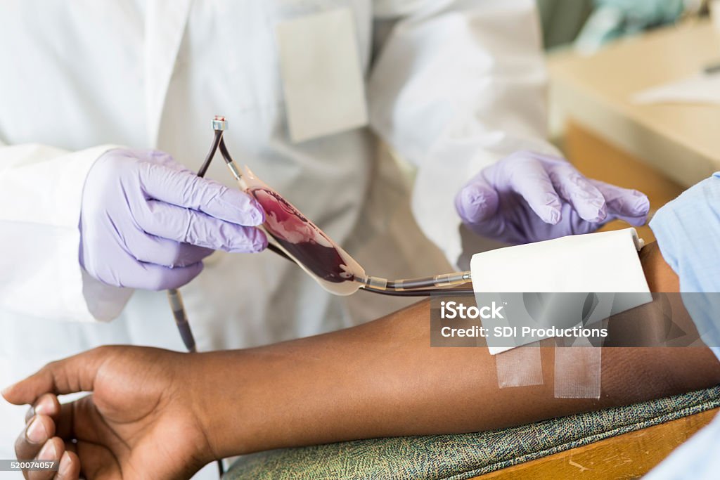 Nurse checking bag of blood while patient gives donation - Royalty-free Bloeddonatie Stockfoto