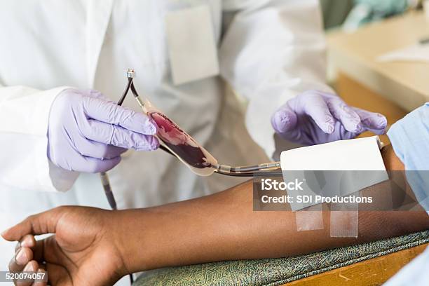 Nurse Checking Bag Of Blood While Patient Gives Donation Stockfoto en meer beelden van Bloeddonatie