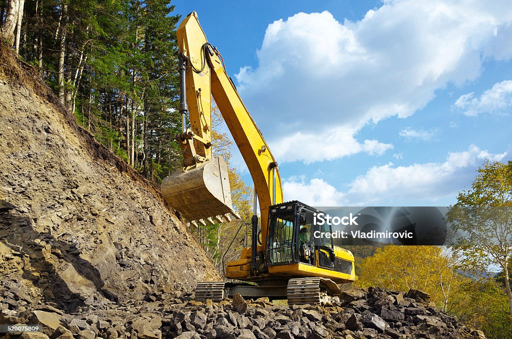 Yellow excavator digging Yellow excavator digging a heap of gravel in forest. Forest Stock Photo