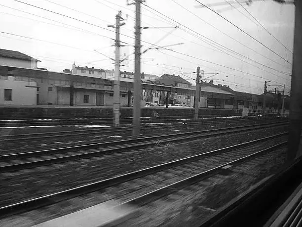 The buildings of a railwaystation speed by seen from a moving train. 
