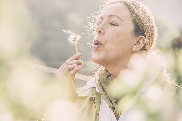 istock Mature woman blowing dandelion flower 520100072