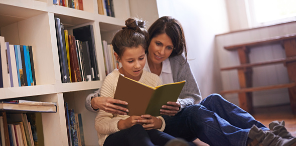 A mother and daughter reading a book together at home