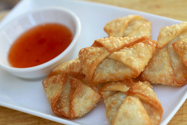 Fried crispy wonton on white plate with dipping sauce