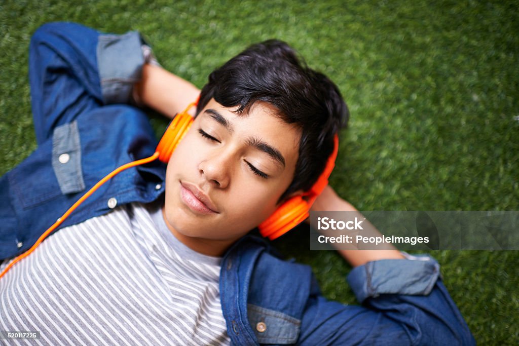 Chilling out with his favourite tunes A young boy relaxing on the lawn and listening to music Eyes Closed Stock Photo