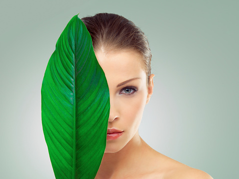 Studio portrait of a beautiful young woman with her face partially covered by a large green leafhttp://azarubaika.com/iStockphoto/2014_05_09_Victoria_Beauty.jpg