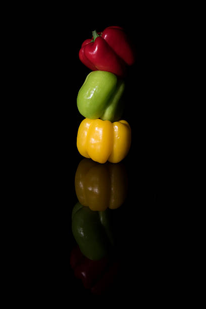 Red, Green, Yellow Bell Peppers with reflection. On black background