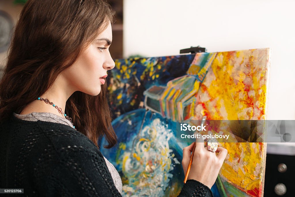 Creative painter paints colorful picture. Closeup Creative painter paints a colorful picture. Closeup of painting process in art workplace. Painter paints in her studio.  Hobbies Stock Photo