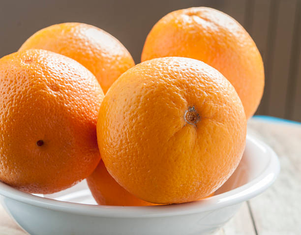 istock orange in white plate on wooden background 520123974
