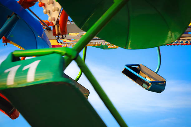 istock Empty seats on flying carnival ride, blue sky background 520123984
