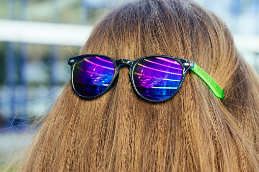 Sun glasses with color glasses on the nape of the girl. Concept of protecting hair from ultraviolet radiation.