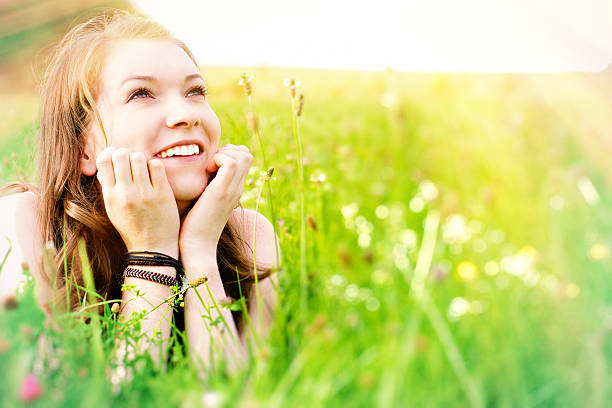 Young pretty woman lying on the grass at summer sun. Natural happiness, fun and harmony.