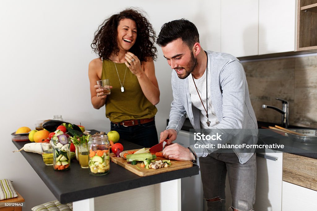 Preparing food at the kitchen Young couple in kitchen preparing together vegetarian meal.Preparing fruit salad.Evening. Cooking Stock Photo