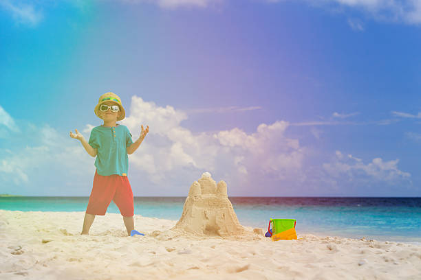 istock happy little boy with built sandcastle on beach 520130445
