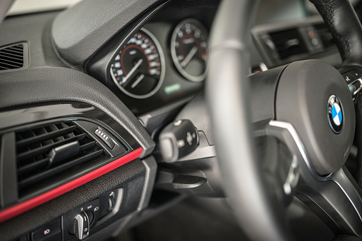 Florence, Italy - October 5, 2014: Interior view of the dashboard and of the steering wheel of the new Bmw 2 series coupe M sport. The steering wheel is the black leather M sport . Studio shot.