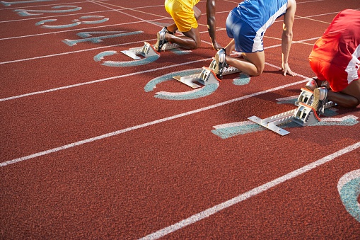Young man training for run race start on a stadium track outside