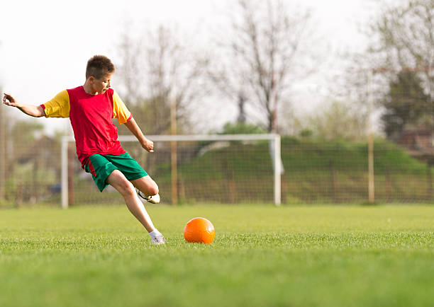 istock boy kicking a ball at goal 520133636